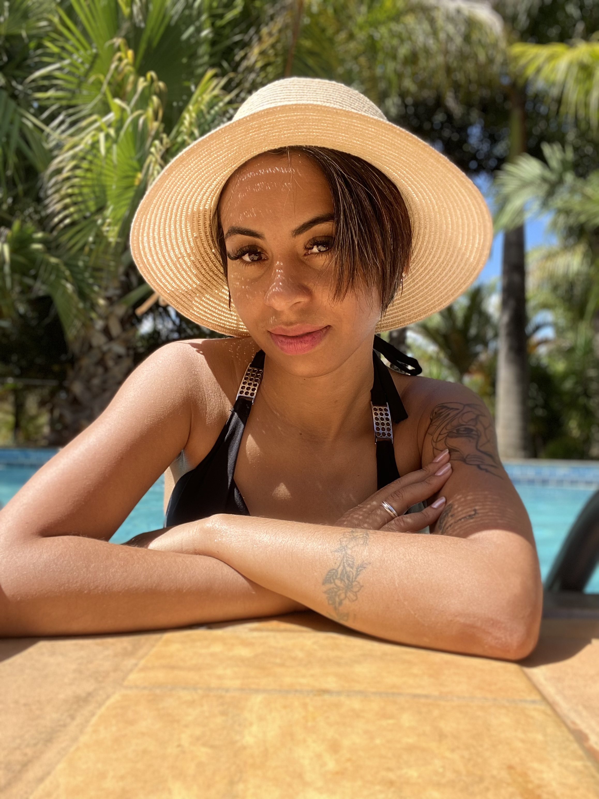 Telma com chapeu debruçada a beira da piscina