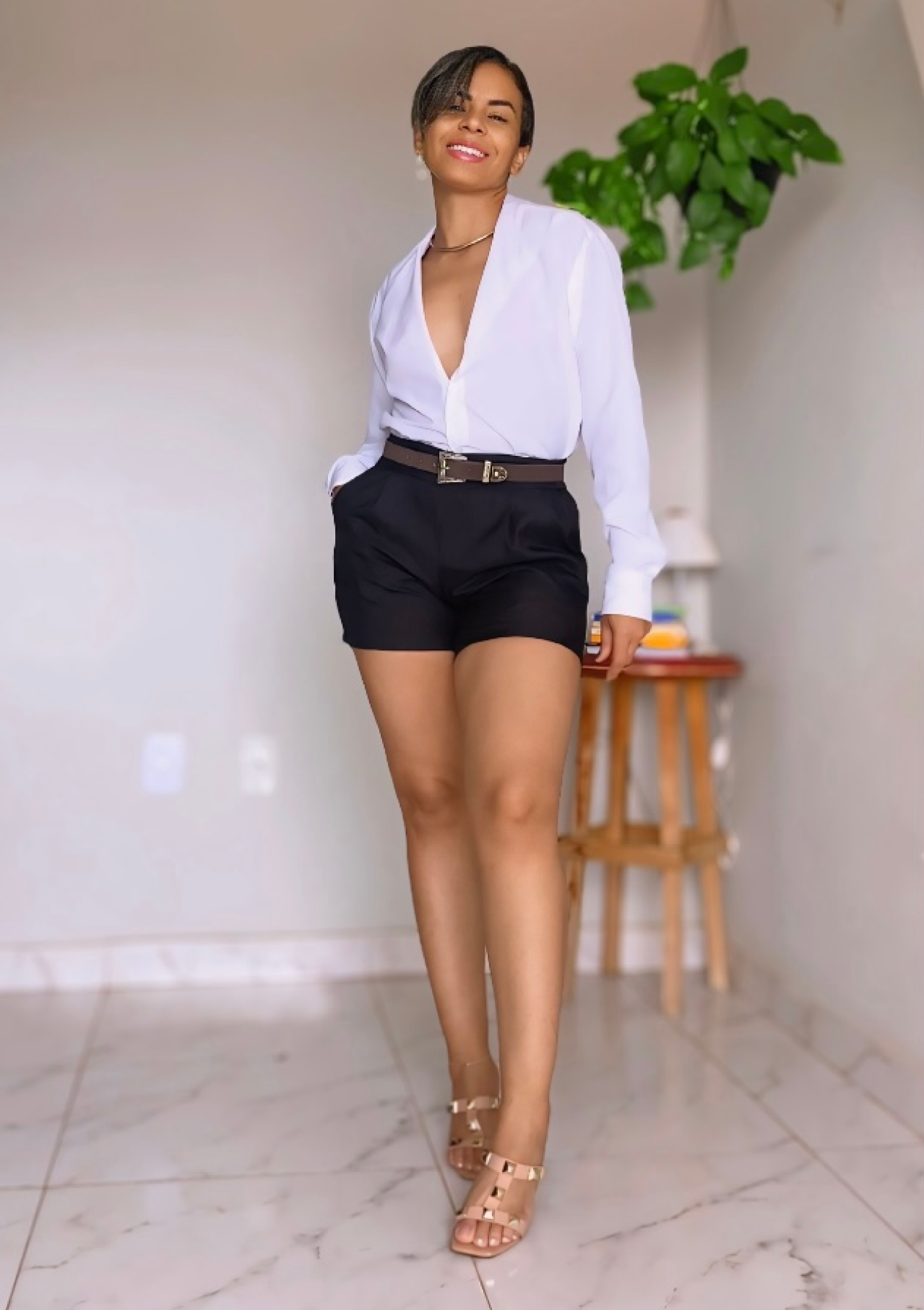 Telma com um look, bermuda preta e camisa branca