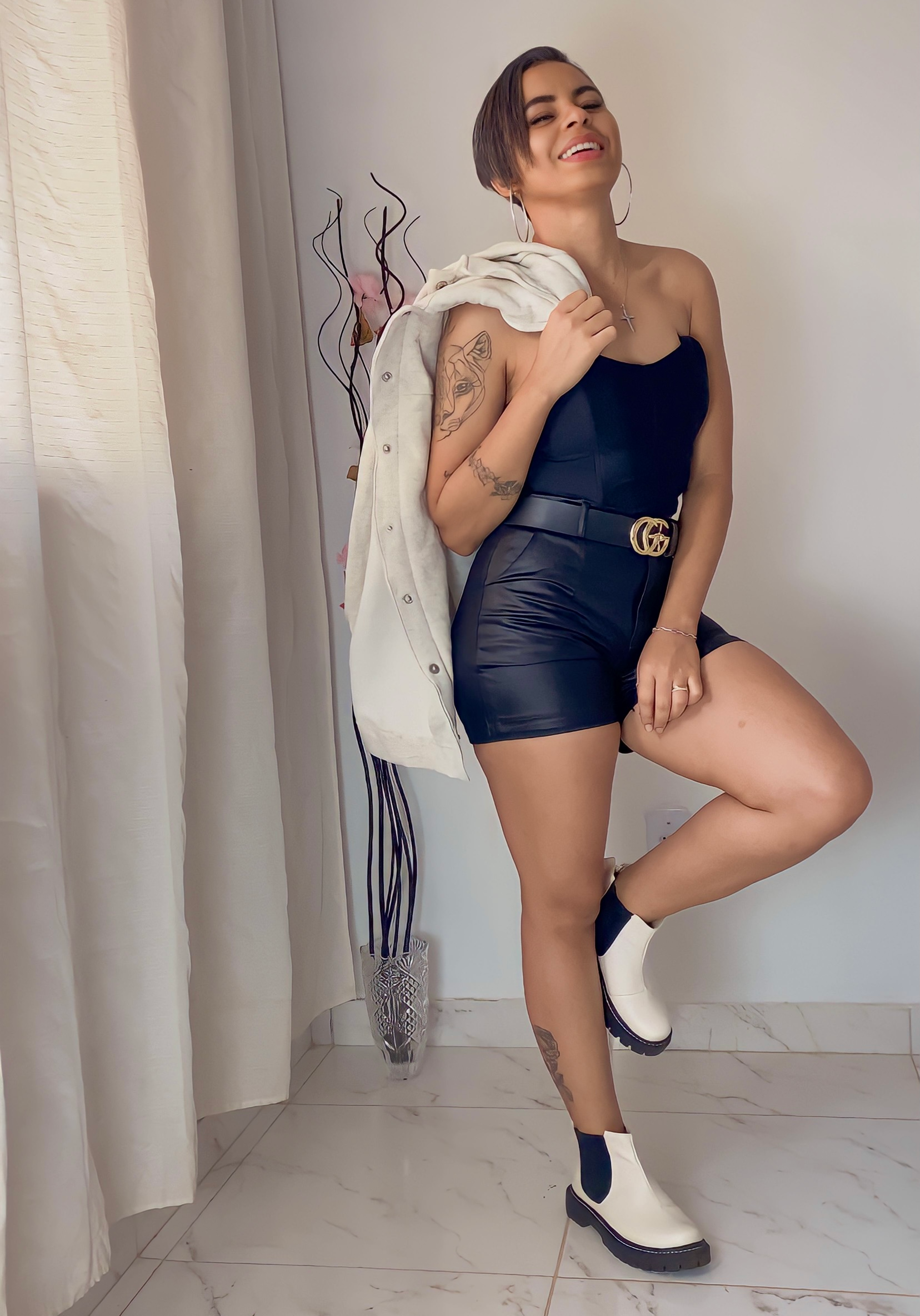 Telma pousando com look, short preto, camisa preta com outra blusa em seu ombro