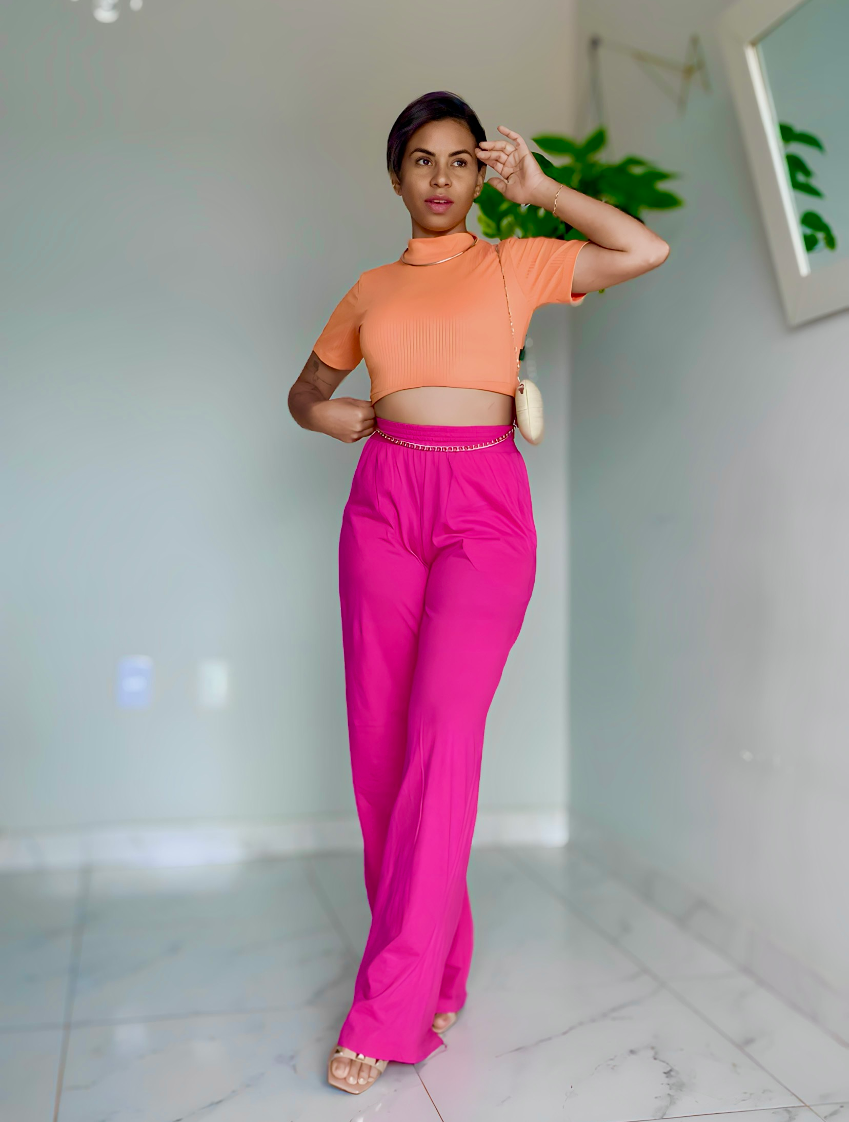 Telma com calça rosa e camisa laranja pousando para foto